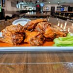 A plate of buffalo wings and celery on a table.