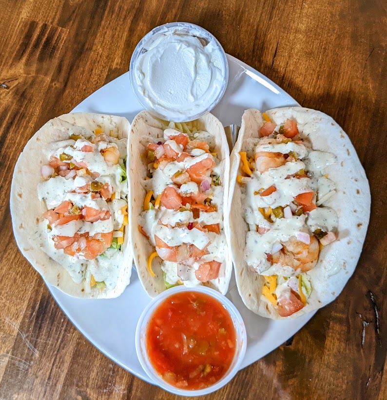 Shrimp tacos with guacamole and sour cream.